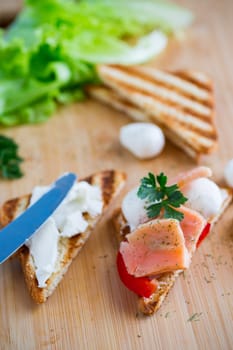 fried toast with salmon, cream cheese, salad, on a wooden table .