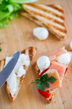 fried toast with salmon, cream cheese, salad, on a wooden table .