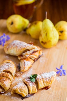 Sweet pastries, puff pastries with pears, on a wooden table .