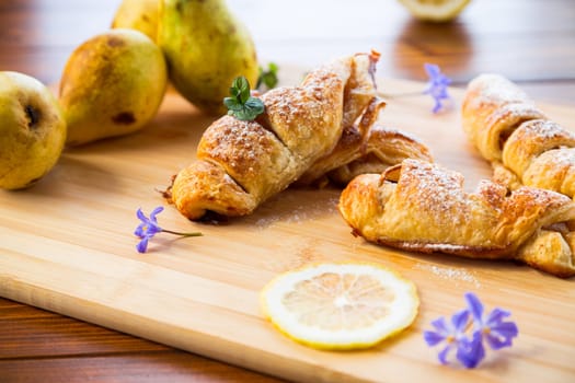 Sweet pastries, puff pastries with pears, on a wooden table .