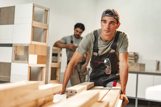 Portrait of young male carpenter standing in the wood workshop close up