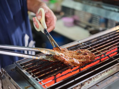 Man use meat tongs grills multiple sliced meat  .