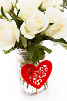 Bouquet of white roses in vase with red heart.