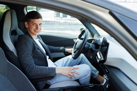Attractive elegant happy man in good car. Confident businessman driving an expensive car and loking at camera