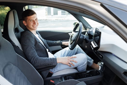 Portrait of an attractive man smiling before starting to work as a taxi driver of a car sharing service on a mobile app. Joyful man driving car, going on trip during summer vacation.