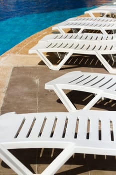 white plastic pool chairs at the swimming pool.