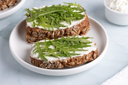 Sandwiches with curd cheese and arugula. Rye bread with seeds.