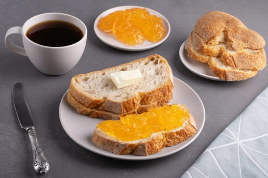 Sandwiches with apricot jam and a cup of coffee on a gray background. Breakfast concept.