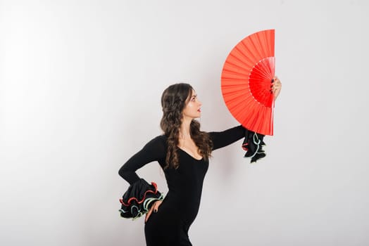 Portrait of beautiful young woman dancing flamenco with fan in studio