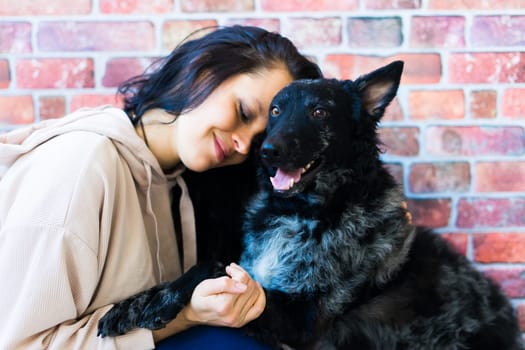 Happy lady in a casual wear hugging purebred pet dog, mudi with owner over studio background.