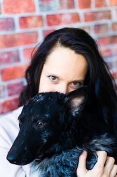 Happy lady in a casual wear hugging purebred pet dog, mudi with owner over studio background.