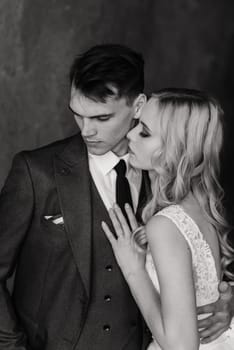 Cute wedding couple in the interior of a classic studio. They kiss and hug each other.