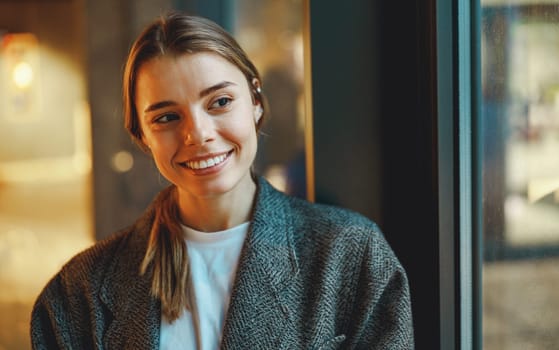 Young female freelancer is standing in coworking near window and looks away. High quality photo