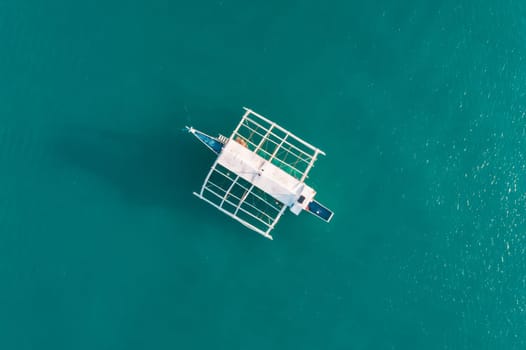 Aerial drone view of boat anchored in the bay with clear and turquoise water. Boat in the tropical lagoon. Tropical landscape.