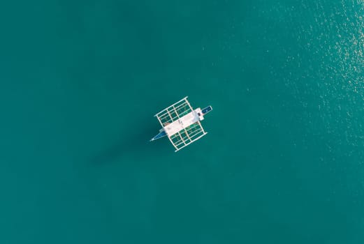 Aerial drone view of boat anchored in the bay with clear and turquoise water. Boat in the tropical lagoon. Tropical landscape.