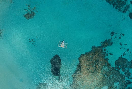 Aerial drone view of boat anchored in the bay with clear and turquoise water. Boat in the tropical lagoon. Tropical landscape.