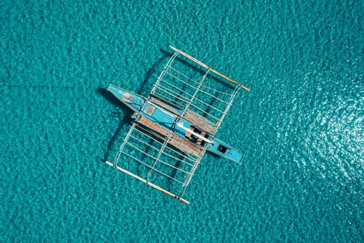 Aerial drone view of boat anchored in the bay with clear and turquoise water. Boat in the tropical lagoon. Tropical landscape.