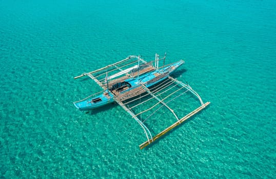 Aerial drone view of boat anchored in the bay with clear and turquoise water. Boat in the tropical lagoon. Tropical landscape.
