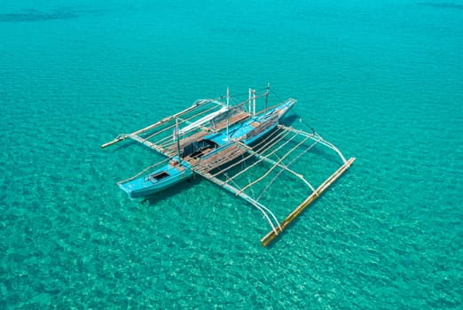 Aerial drone view of boat anchored in the bay with clear and turquoise water. Boat in the tropical lagoon. Tropical landscape.