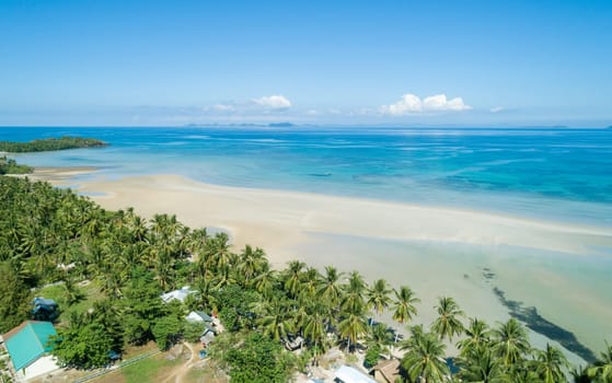 Aerial view of tropical sandy beach in bay with blue water. Seascape with sea, sand, palm trees. Top view of paradise island.