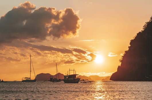 Beautiful sunset with silhouettes of philippine boats in El Nido, Palawan island, Philippines