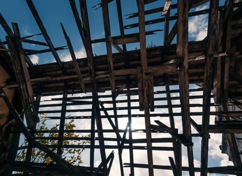 Bottom view of the roof of an old building with wooden structures against the sky. Destroyed wooden roof in the abandoned building.