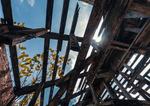 Bottom view of the roof of an old building with wooden structures against the sky. Destroyed wooden roof in the abandoned building.