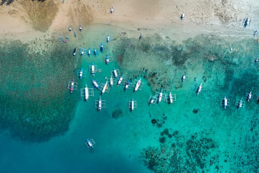 Top drone view of a traditional philippine boats on the surface of the azure water in the lagoon. Summer and travel vacation concept