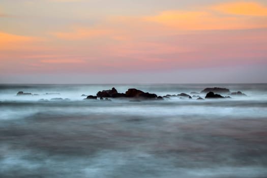 Waves crash along the coastline during sunset near San Simeon, California.