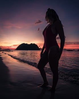 Serene sunset silhouette of a woman standing on a beach during twilight