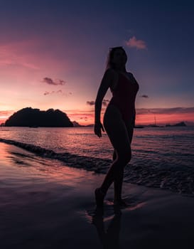 Serene sunset silhouette of a woman standing on a beach during twilight