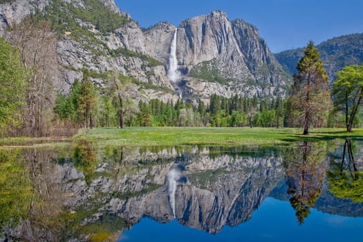 Yosemite Falls is reflected in the waters of the Merced River at Yosemite National Park, California