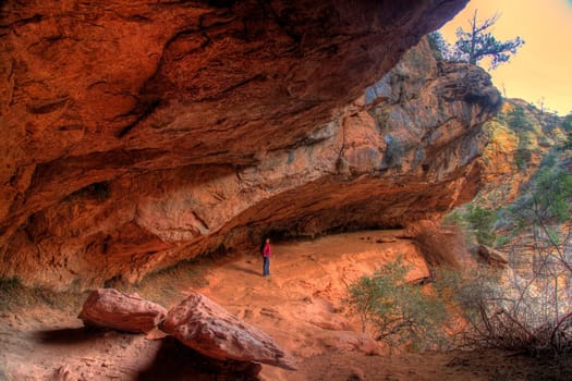 A hiker peers out from under an alcove at Zion National Park, Utah