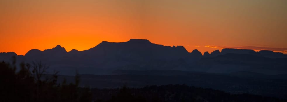 The sun sets behind the skyline of Zion National park, Utah