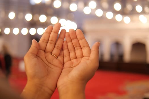 Muslim young woman in hijab is praying in mosque