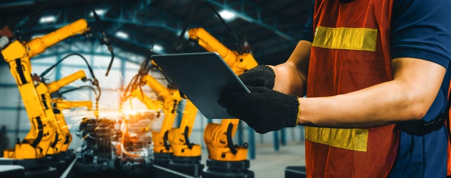 XAI Engineer use advanced robotic software to control industry robot arm in factory. Automation manufacturing process controlled by specialist using IOT software connected to internet network.