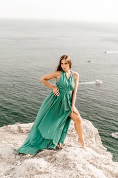 Woman sea green dress. Side view a happy woman with long hair in a long mint dress posing on a beach with calm sea bokeh lights on sunny day. Girl on the nature on blue sky background