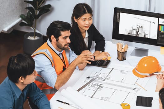 Diverse group of civil engineer and client working together on architectural project, reviewing construction plan and building blueprint at meeting table. Prudent