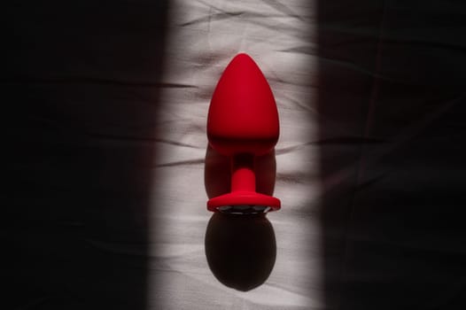 Red silicone anal plug on a white sheet