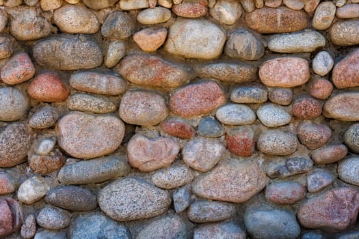 wall made of many colorful round stones, full-frame background and texture.