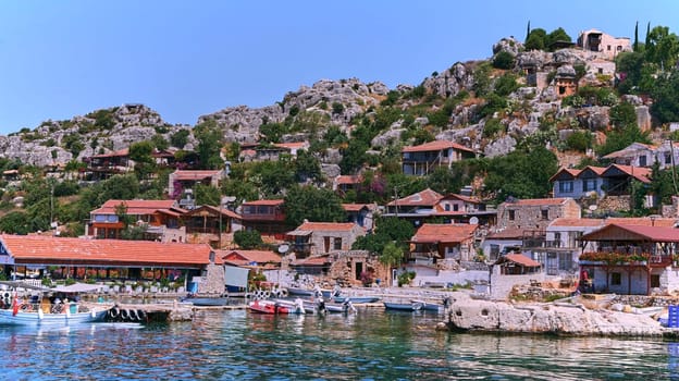 Charming Mediterranean village on Turkish coast with red-roofed houses, historic stone castle, and stunning sea views, perched on cliffs overlooking the azure waters of the Mediterranean Sea.