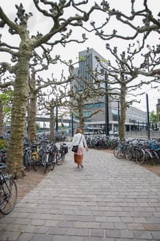 Ghent, Belgium, May 5, 2022: Virginie Loveling Building, Flemish Community Center, Modern City, young woman walks towards the building through the parking lot with bicycles,High quality photo