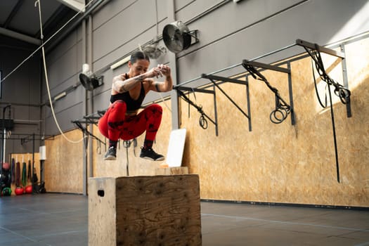 Horizontal photo with copy space of a woman jumping on a box in a cross training gym