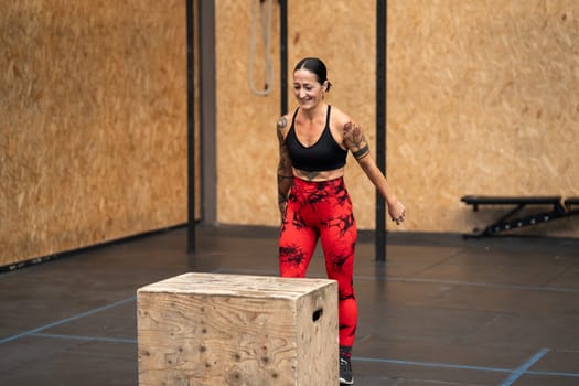 Happy strong adult woman about to jump into box in a gym