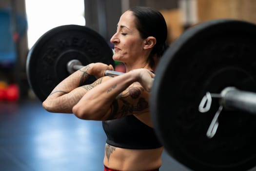 Sportive strong woman doing an effort to lift weights in a cross training gym