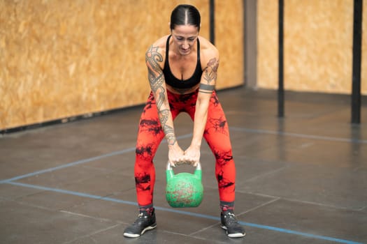 Strong mature woman working out using kettlebell in a gym
