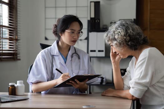 A beautiful female doctor is sitting giving health advice and encouragement in taking care of her health to an elderly retired woman with health problems..