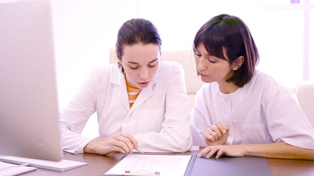 Two female doctor consulting a medical report in a desk