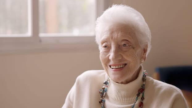 Old woman with white hair smiling at camera in a geriatric looking to the copy space