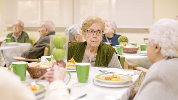 Some senior woman chatting and eating in a dining room of geriatric